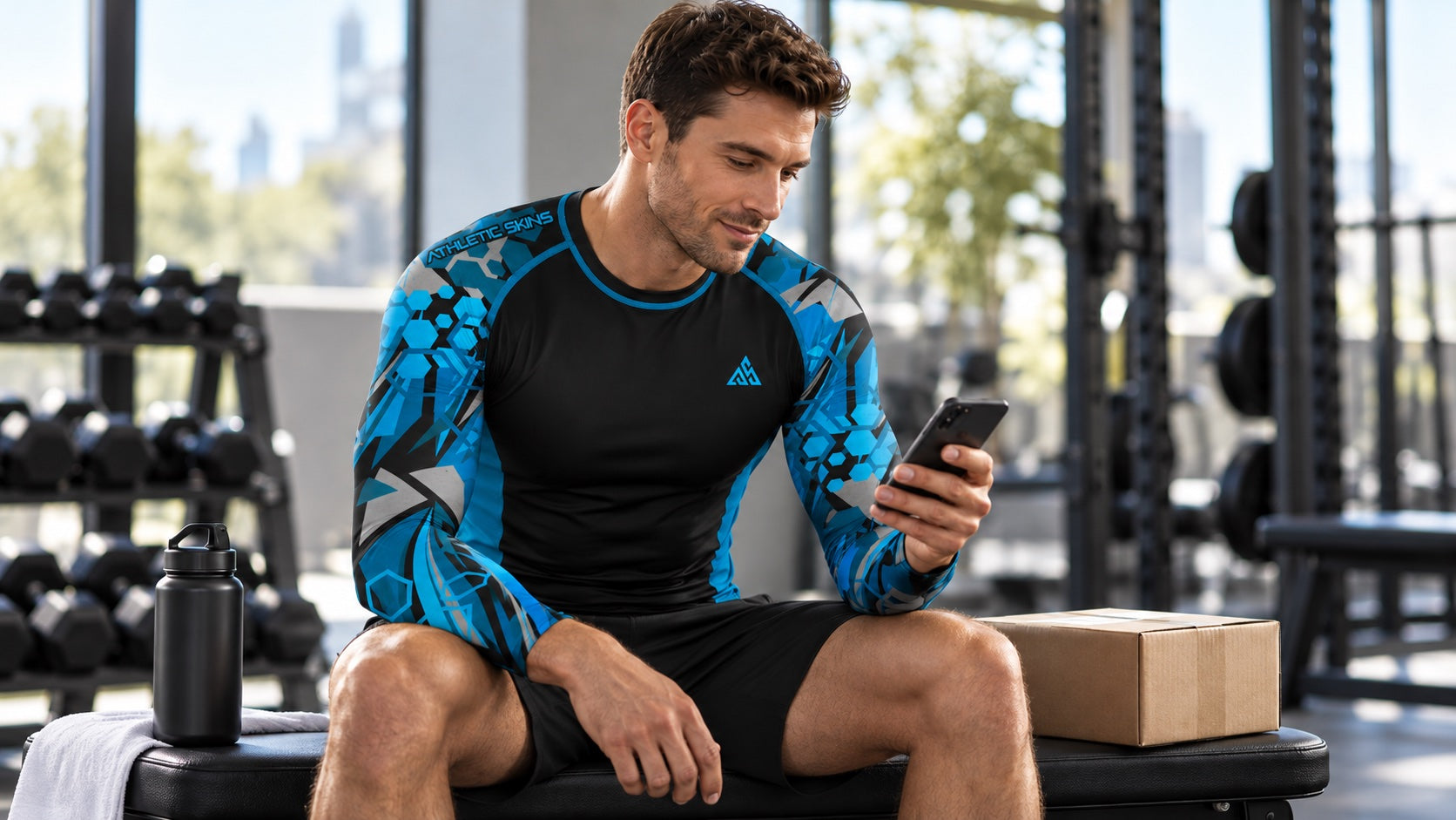 Fictional athlete in a Black/Blue Athletic Skins long-sleeve top checking a phone beside a parcel at a gym.